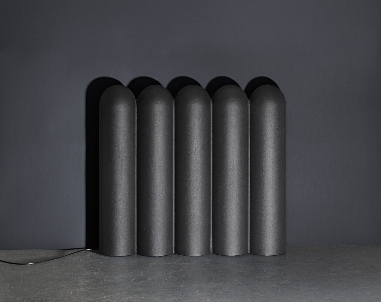 Caleo : objet lumineux éteint en fonderie d'aluminium gris anthracite. Design suisse Bertille Laguet. Fabrication française par l'artiste elle-même.