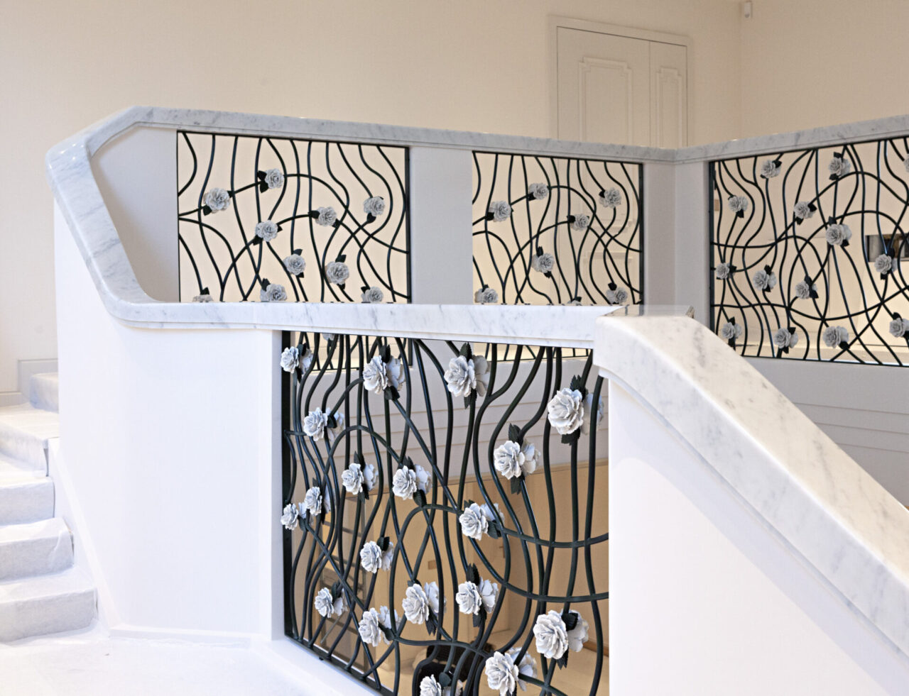La roseraie : rampe d'escalier en fer forgé vert foncé garni de roses blanches. Design et fabrication Bertille Laguet.
