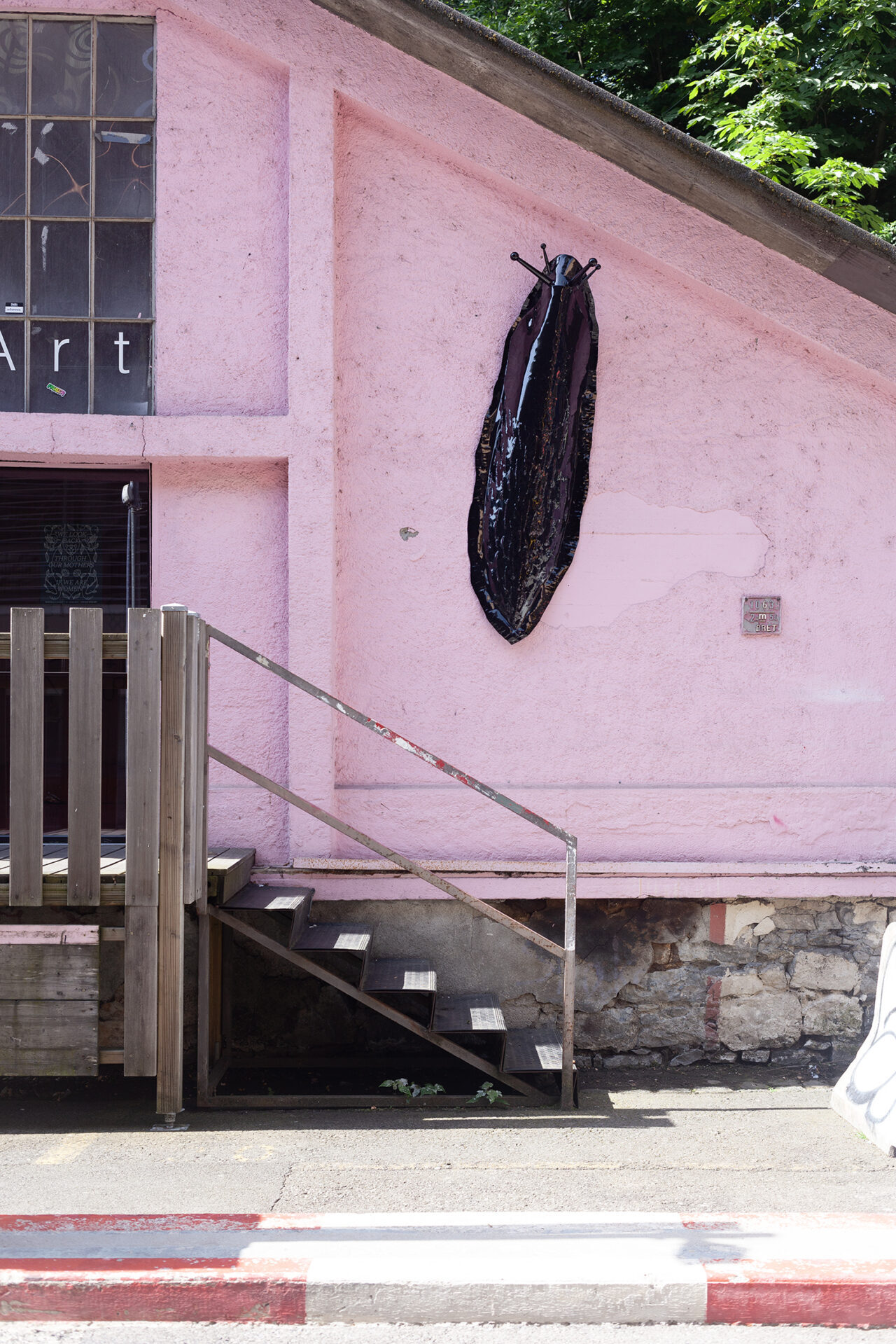 Limace géante métallique noire sur une façade rose